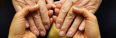 Young hands holding the hands of an older adult